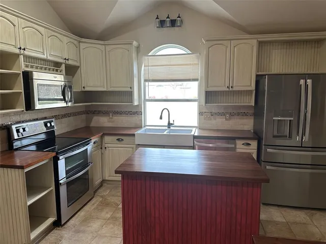 a kitchen with kitchen island granite countertop a sink stove and refrigerator