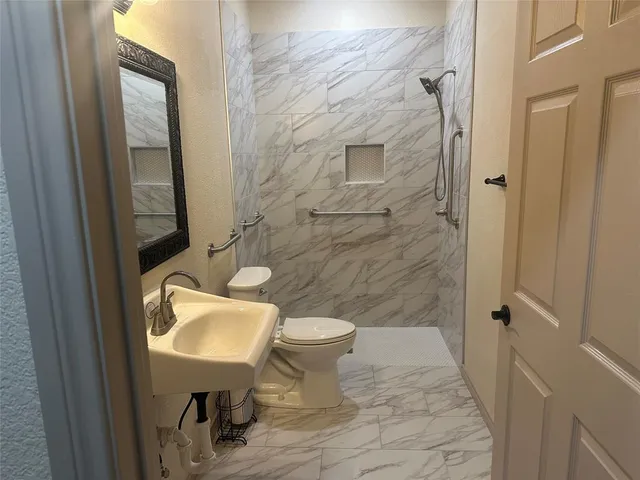a bathroom with a sink a toilet and shower