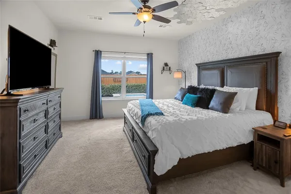 a bedroom with a bed and a flat tv screen on dresser