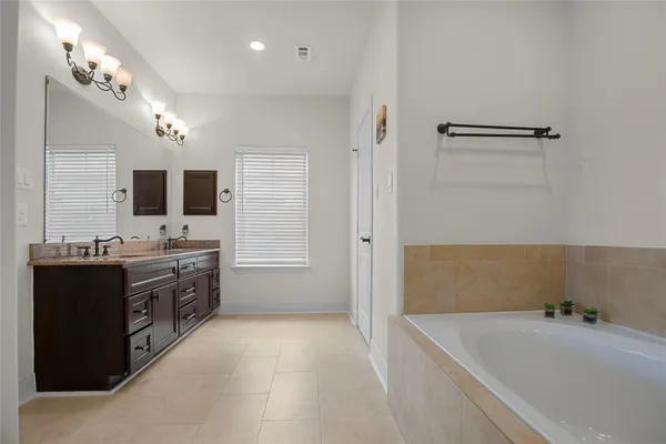 a spacious bathroom with a tub sink and mirror