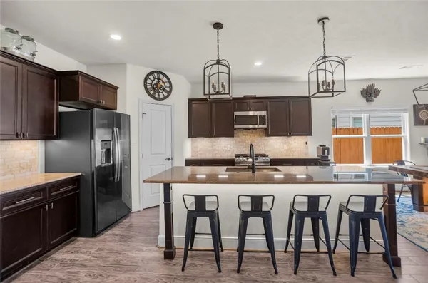 a kitchen with stainless steel appliances granite countertop a dining table chairs sink and stove