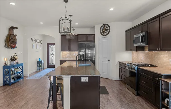 a kitchen with stainless steel appliances granite countertop a stove a refrigerator a sink dishwasher with wooden floor and cabinets