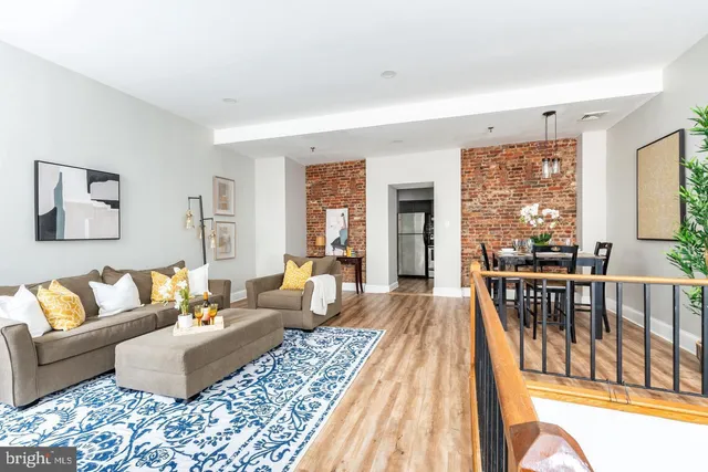 a living room with furniture wooden floor and a floor to ceiling window