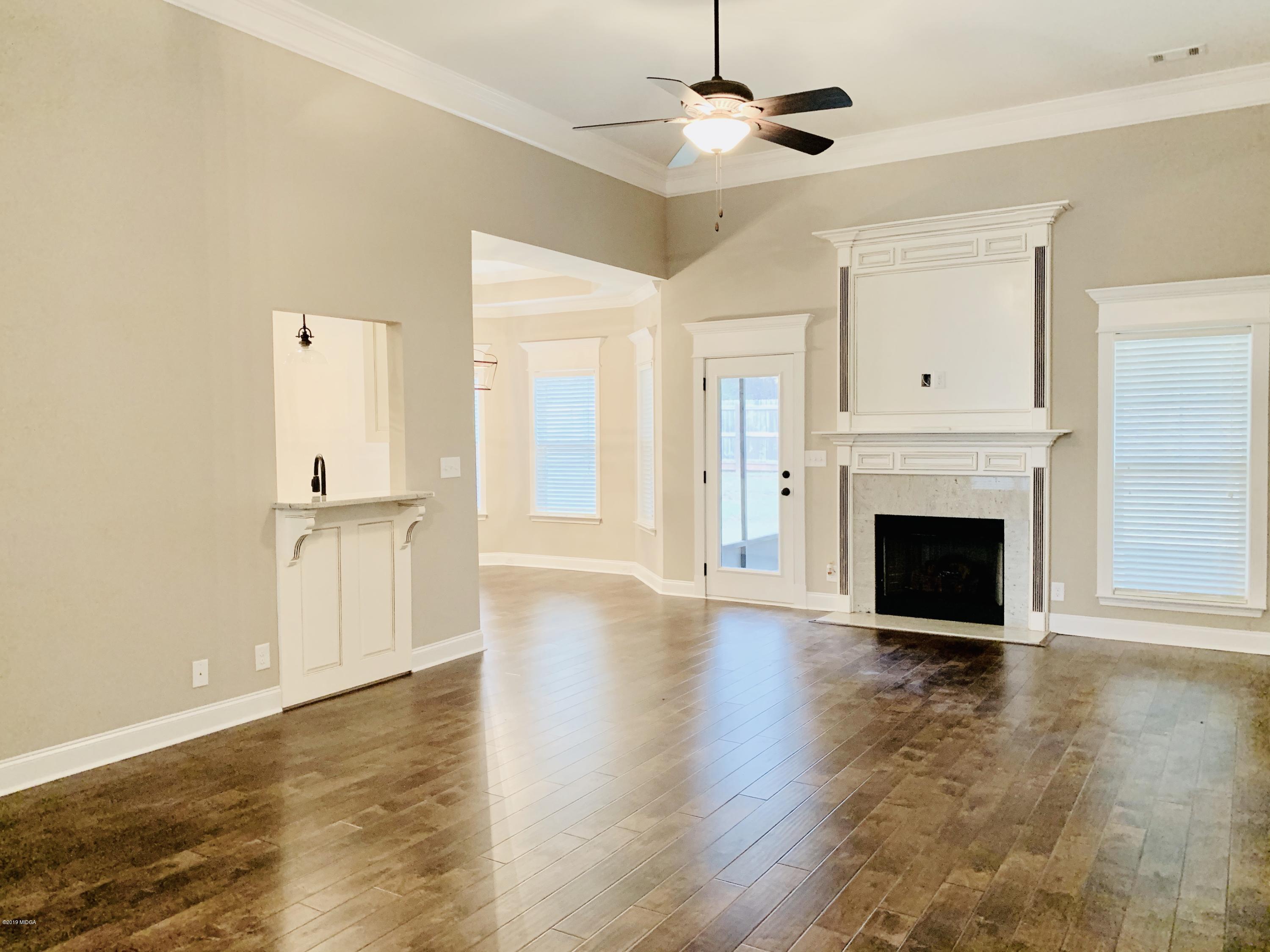 208 Bridgehampton Way Perry, GA 31069 - Photo 4 of 37 an empty room with wooden floor fireplace and windows