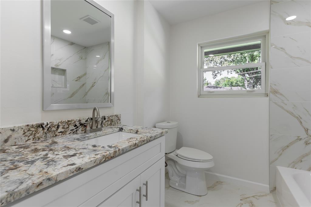 9225 Plano Road Dallas, TX 75238 - Photo 13 of 24 a bathroom with a granite countertop toilet a sink and a mirror