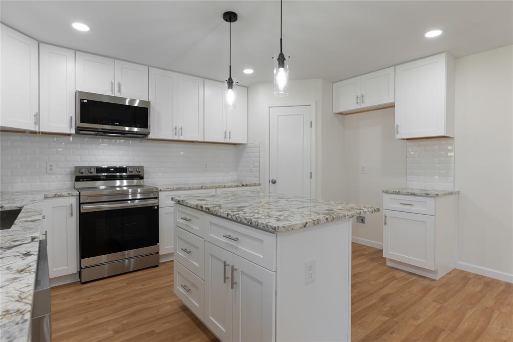 9225 Plano Road Dallas, TX 75238 - Photo 10 of 24 a kitchen with stainless steel appliances granite countertop a sink a stove a refrigerator and white cabinets with wooden floor