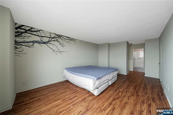 a spacious bedroom with a bed and wooden floor