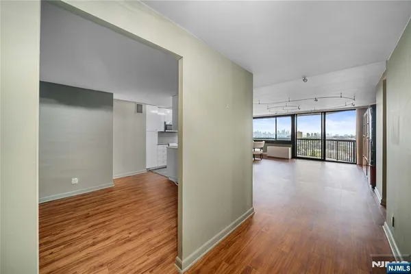 a view of an empty room with wooden floor and a window