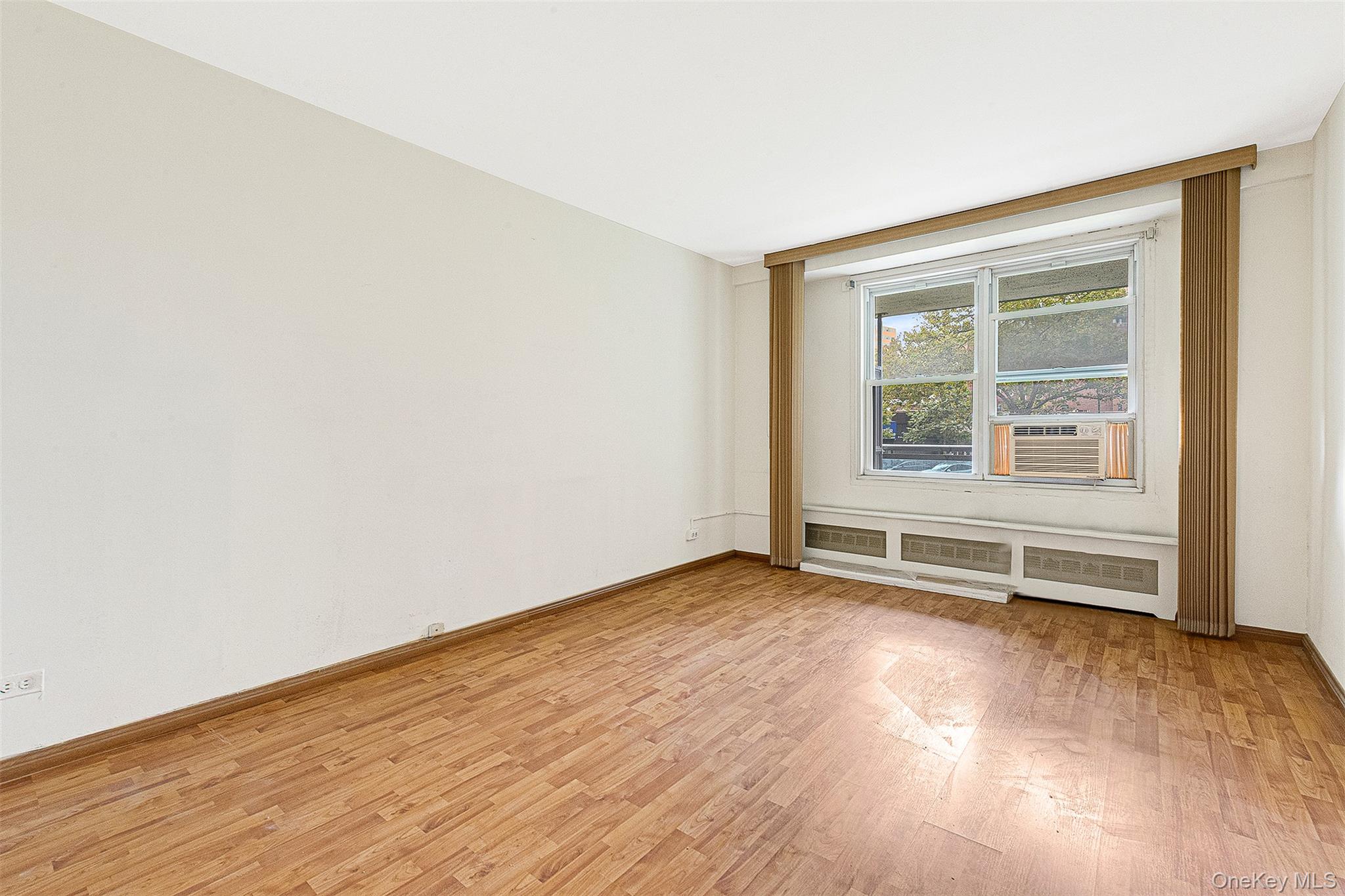 97-37 63rd Road, Unit 2/B Queens, NY 11374 - Photo 19 of 26 an empty room with wooden floor and windows