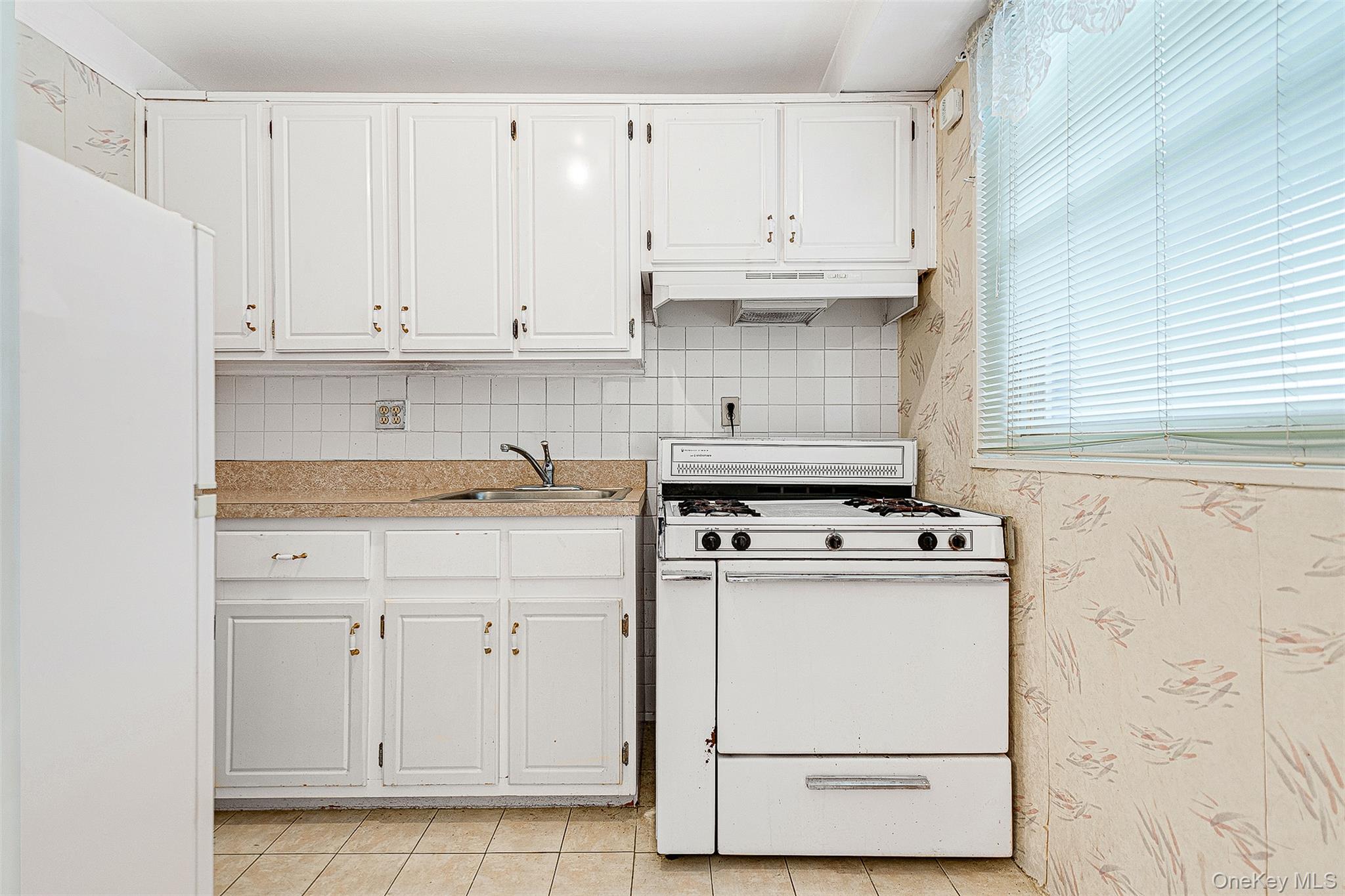 97-37 63rd Road, Unit 2/B Queens, NY 11374 - Photo 5 of 26 a kitchen with white cabinets and white appliances