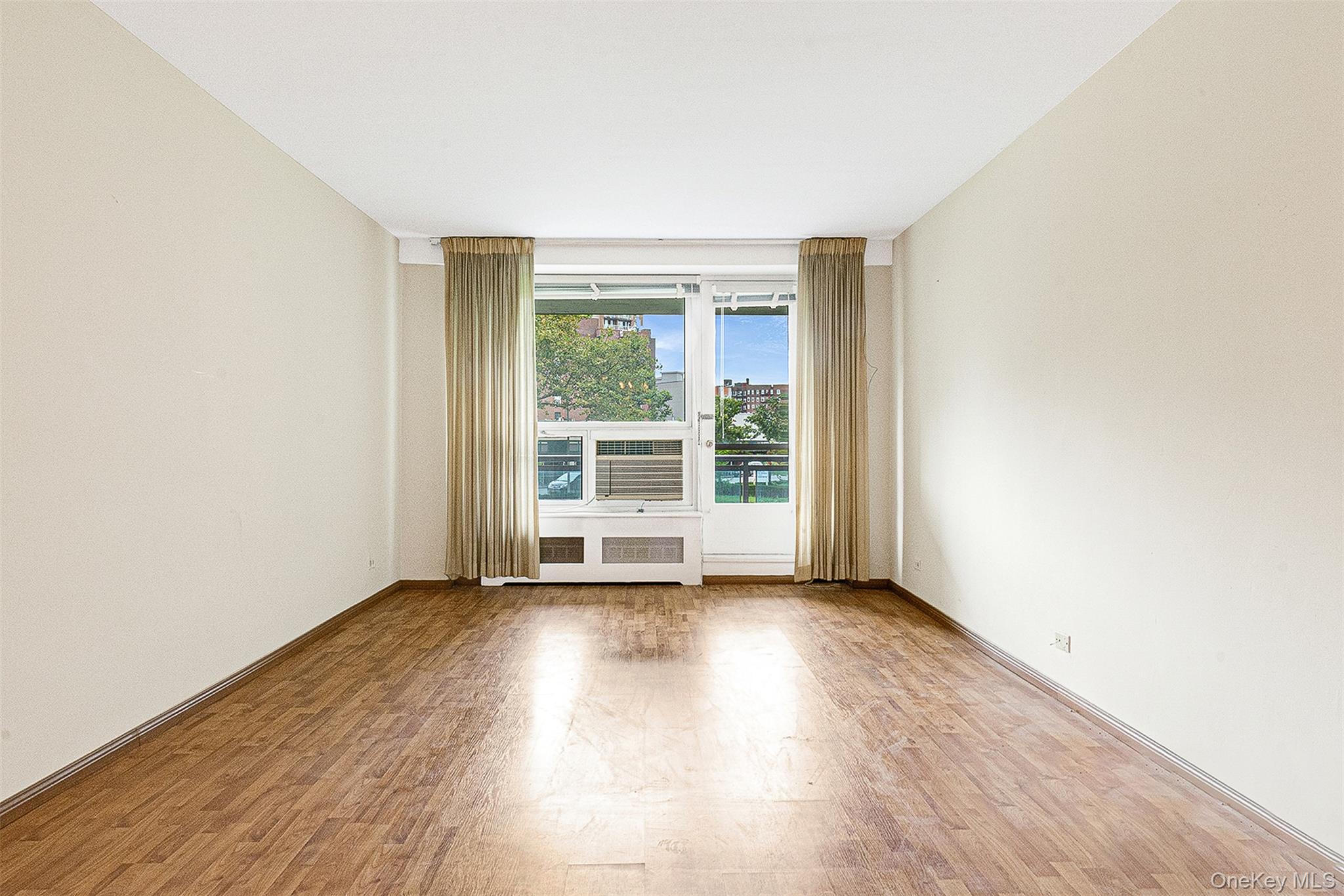 97-37 63rd Road, Unit 2/B Queens, NY 11374 - Photo 10 of 26 an empty room with wooden floor and windows