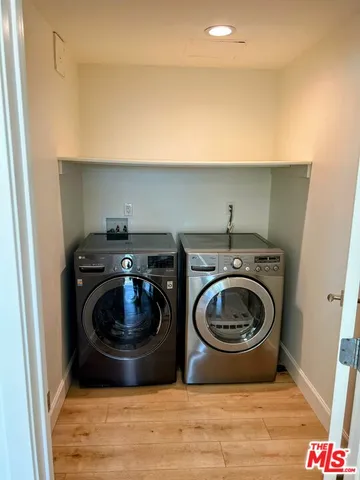 a view of washer and dryer in a utility room with wooden floor
