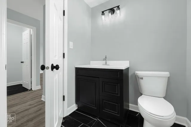 a bathroom with a toilet a sink and wooden floor