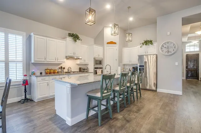 a kitchen with granite countertop kitchen island stainless steel appliances a dining table and chairs