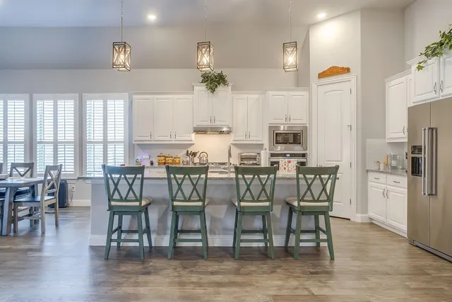 a kitchen with stainless steel appliances kitchen island granite countertop a table chairs and a refrigerator