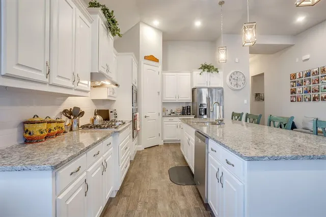 a kitchen with stainless steel appliances kitchen island granite countertop a table chairs and a refrigerator