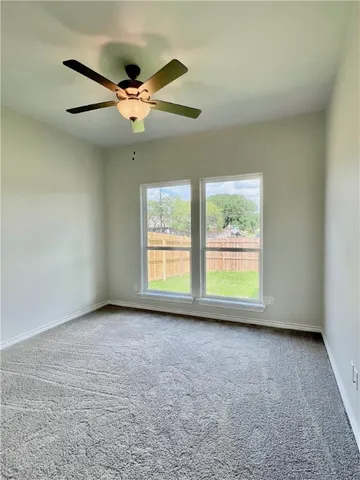 an empty room with windows and ceiling fan