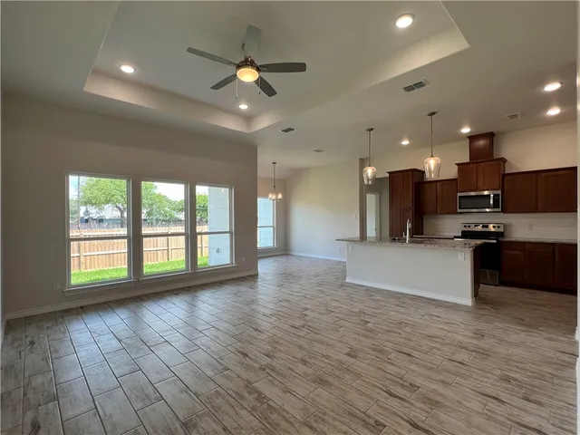 a view of an empty room with kitchen appliances and a large window