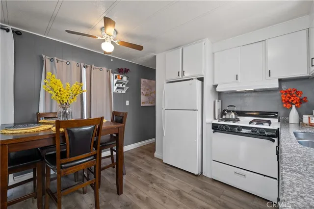 a kitchen with stainless steel appliances granite countertop a stove a refrigerator a microwave a dining table and chairs with wooden floor