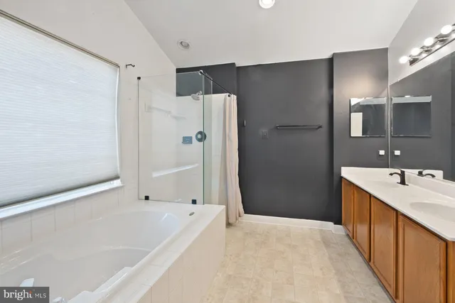 a bathroom with a tub shower vanity and a sink