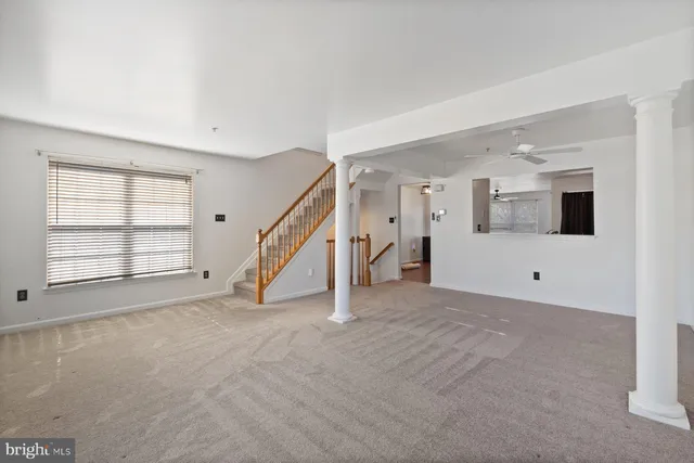 a view of an empty room with a window and a kitchen