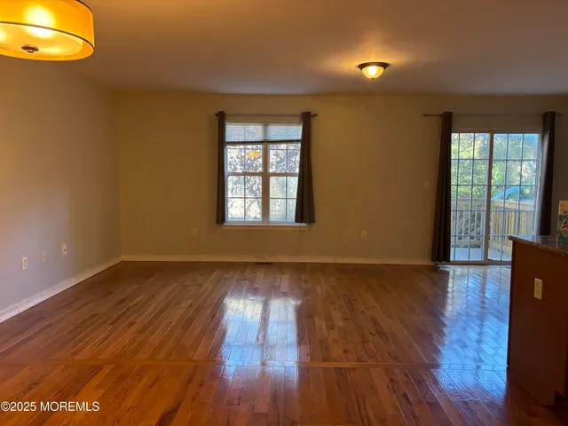 a view of an empty room with window and wooden floor