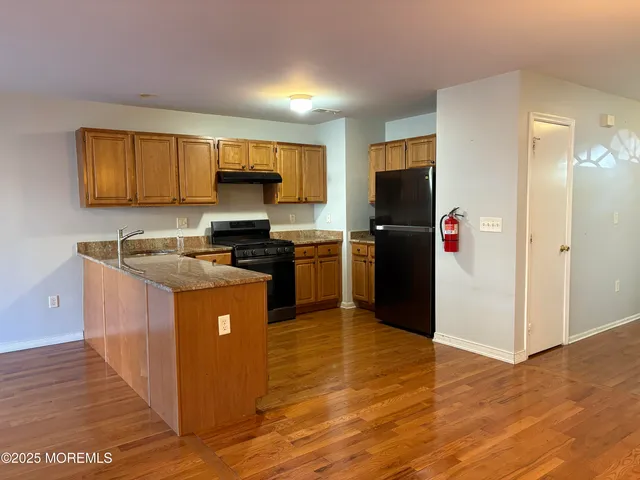 a kitchen with granite countertop a refrigerator stove and cabinets
