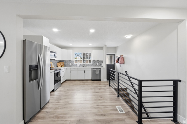 1795 South 200 West Bountiful, UT 84010 - Photo 8 of 37 Kitchen featuring stainless steel appliances, white cabinetry, light countertops, light wood-style flooring, and recessed lighting