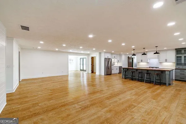 a view of an empty room with kitchen and window