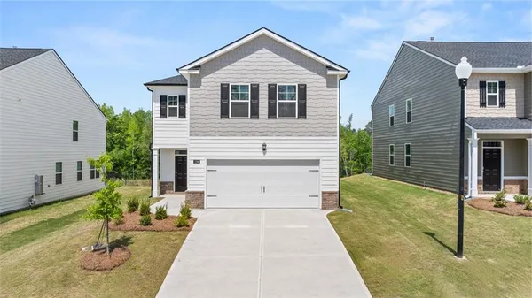 a view of house and a yard with garage