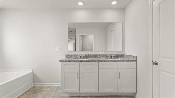 a bathroom with a granite countertop sink a toilet a mirror and bathtub