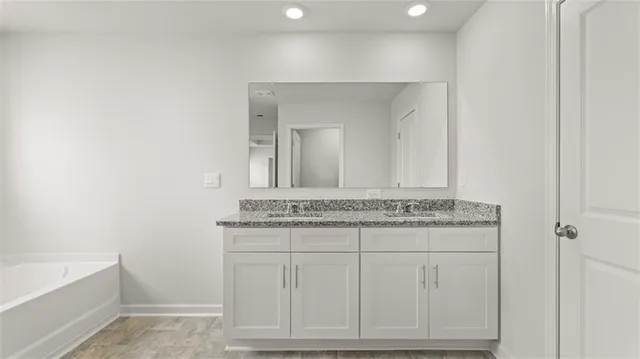 a bathroom with a granite countertop sink a toilet a mirror and bathtub