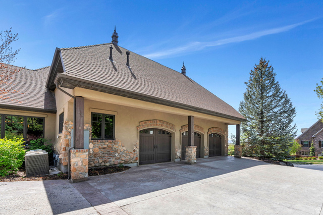 811 South High Ridge Drive Alpine, UT 84004 - Photo 89 of 98 View of property exterior with driveway, stucco siding, stone siding, an attached garage, and roof with shingles