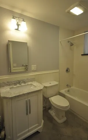 a bathroom with a granite countertop toilet sink and mirror