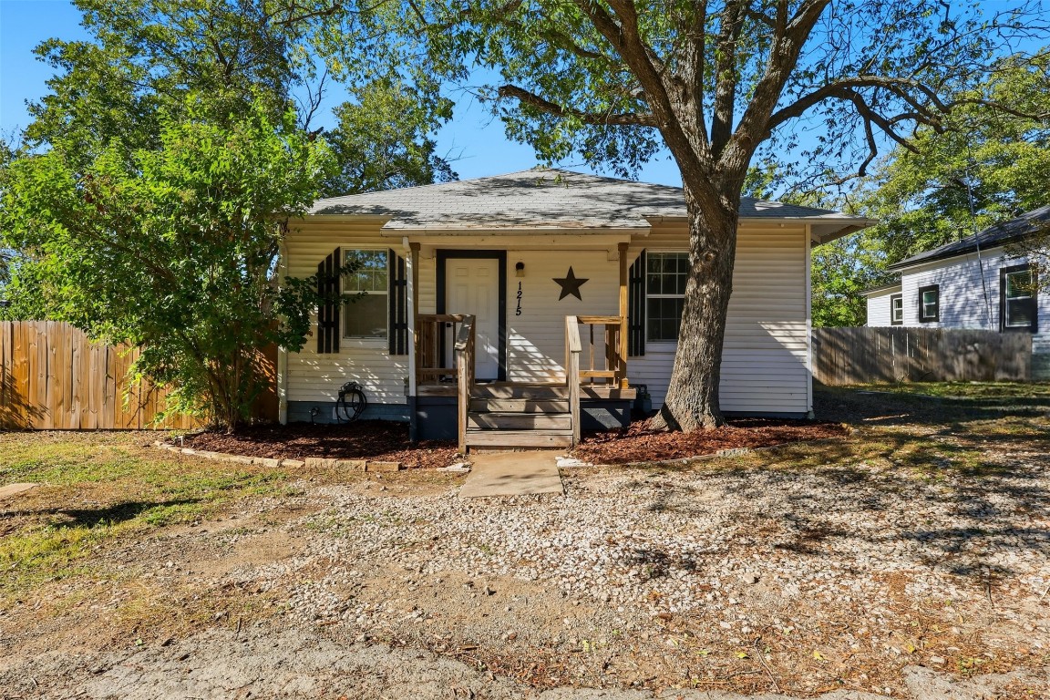 a view of a house with a large tree and wooden fence