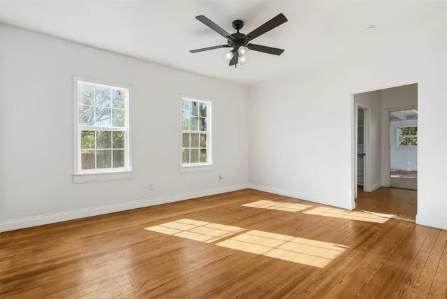 a view of empty room with wooden floor and fan