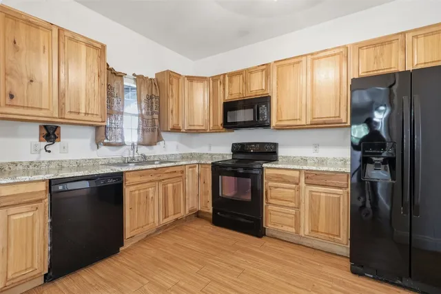 a kitchen with granite countertop a refrigerator stove top oven and sink