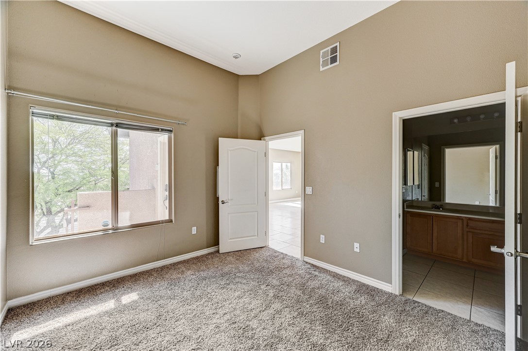 8985 South Durango Drive, Unit 2187 Las Vegas, NV 89113 - Photo 3 of 73 A spacious bedroom provides a comfortable retreat with a large window and convenient bathroom access.