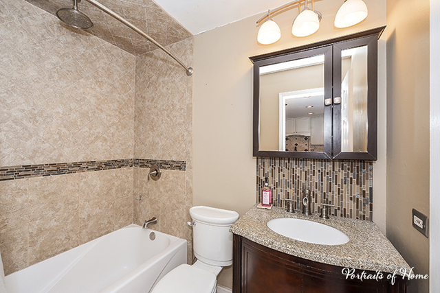 1900 Light Road, Unit 102 Oswego, IL 60543 - Photo 4 of 10 a bathroom with a granite countertop sink mirror vanity and toilet