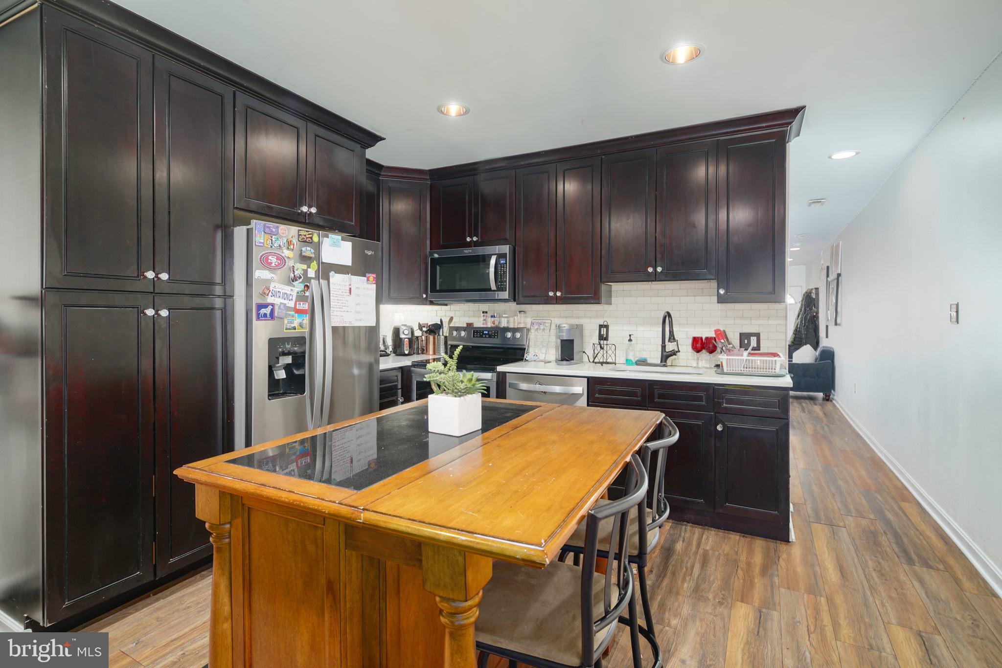 a kitchen with granite countertop stainless steel appliances a refrigerator and a stove top oven