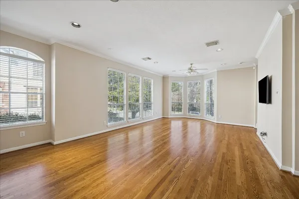 a view of an empty room with wooden floor and a window