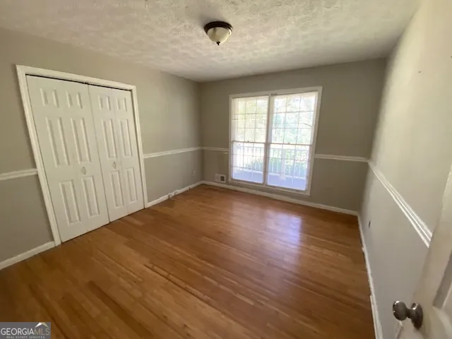 an empty room with wooden floor and windows