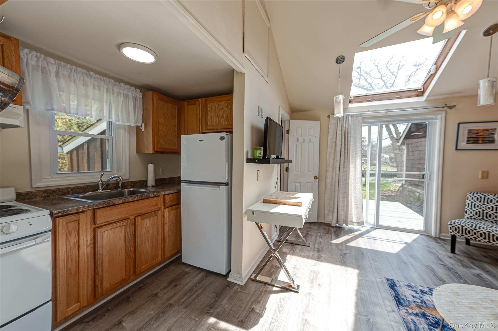 18 Shinnecock Road, Unit 2 Hampton Bays, NY 11946 - Photo 6 of 7 a kitchen with stainless steel appliances granite countertop a refrigerator a stove a sink dishwasher and white countertops with wooden floor