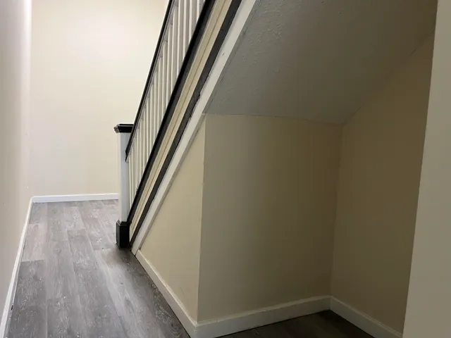 a view of a hallway with wooden floor and stairs