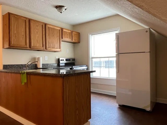 a kitchen with granite countertop a refrigerator sink and cabinets