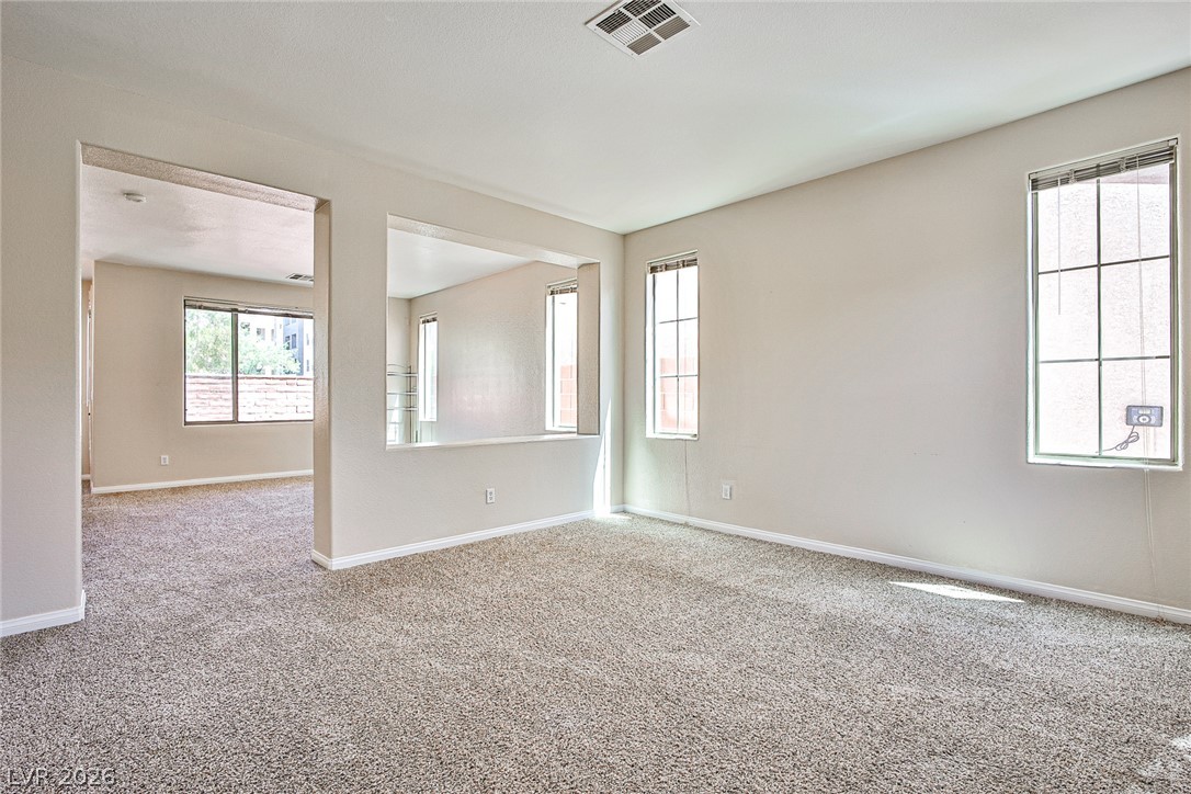 An open doorway and wall cutout connect this carpeted living room to adjacent spaces.