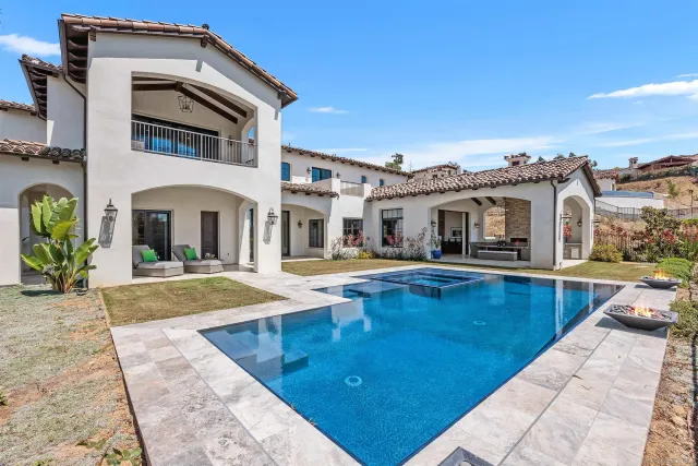 a view of a white building with a swimming pool and porch