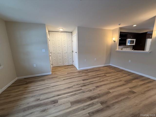 373 Woodbridge Drive, Unit B Ridge, NY 11961 - Photo 12 of 25 Unfurnished living room featuring new wood finished floors and baseboards Open to the Kitchen.