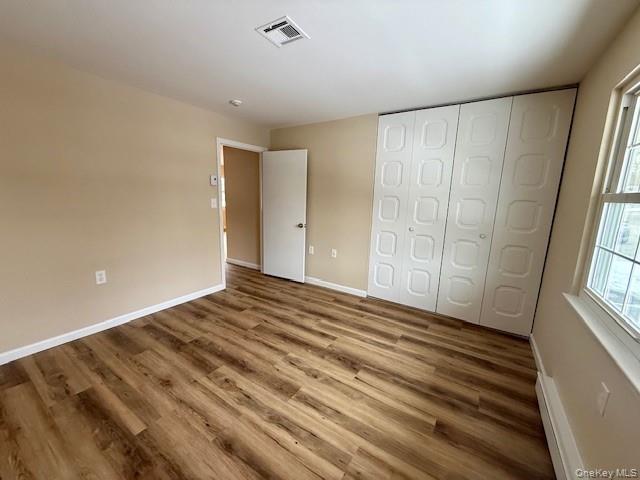 373 Woodbridge Drive, Unit B Ridge, NY 11961 - Photo 17 of 25 Unfurnished bedroom with New wood finished floors, a closet, and baseboard heating