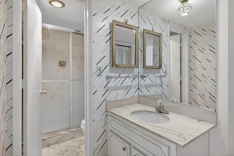 a bathroom with a granite countertop sink a mirror and shower
